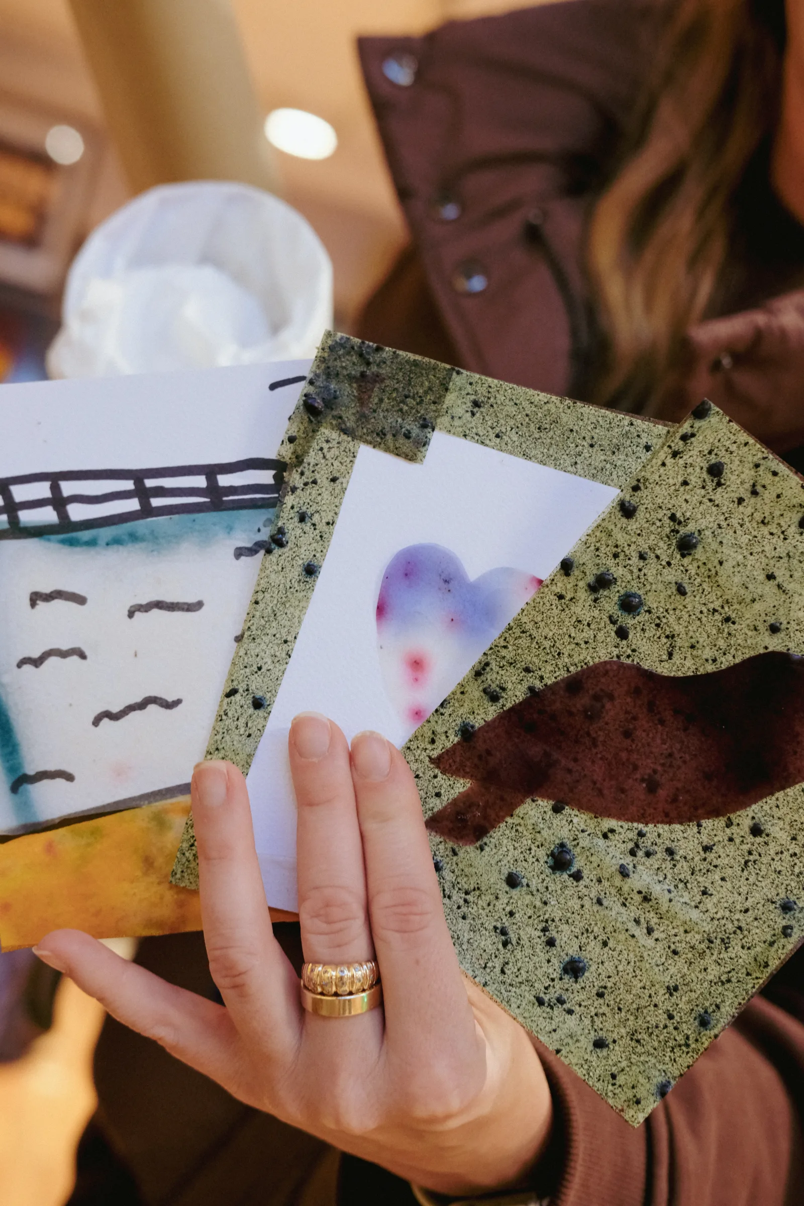 Manos sosteniendo muestras de material, entre ellas una textura verde de conchas trituradas con una forma recortada
