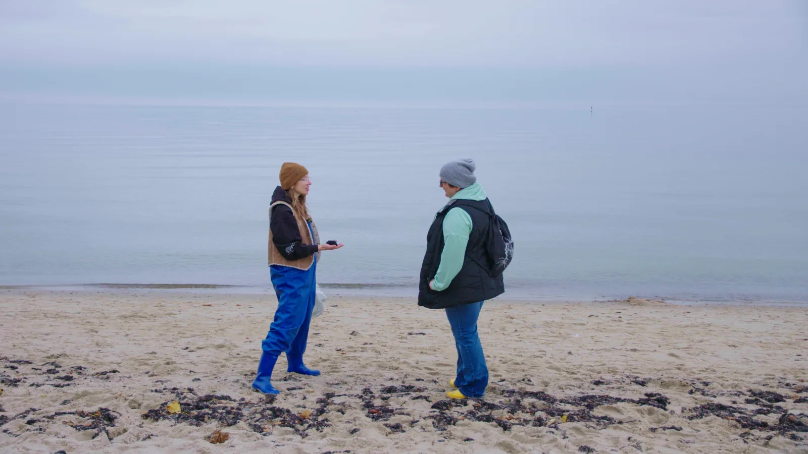 Dos personas conversando en la orilla del mar sobre un minimalista horizonte báltico