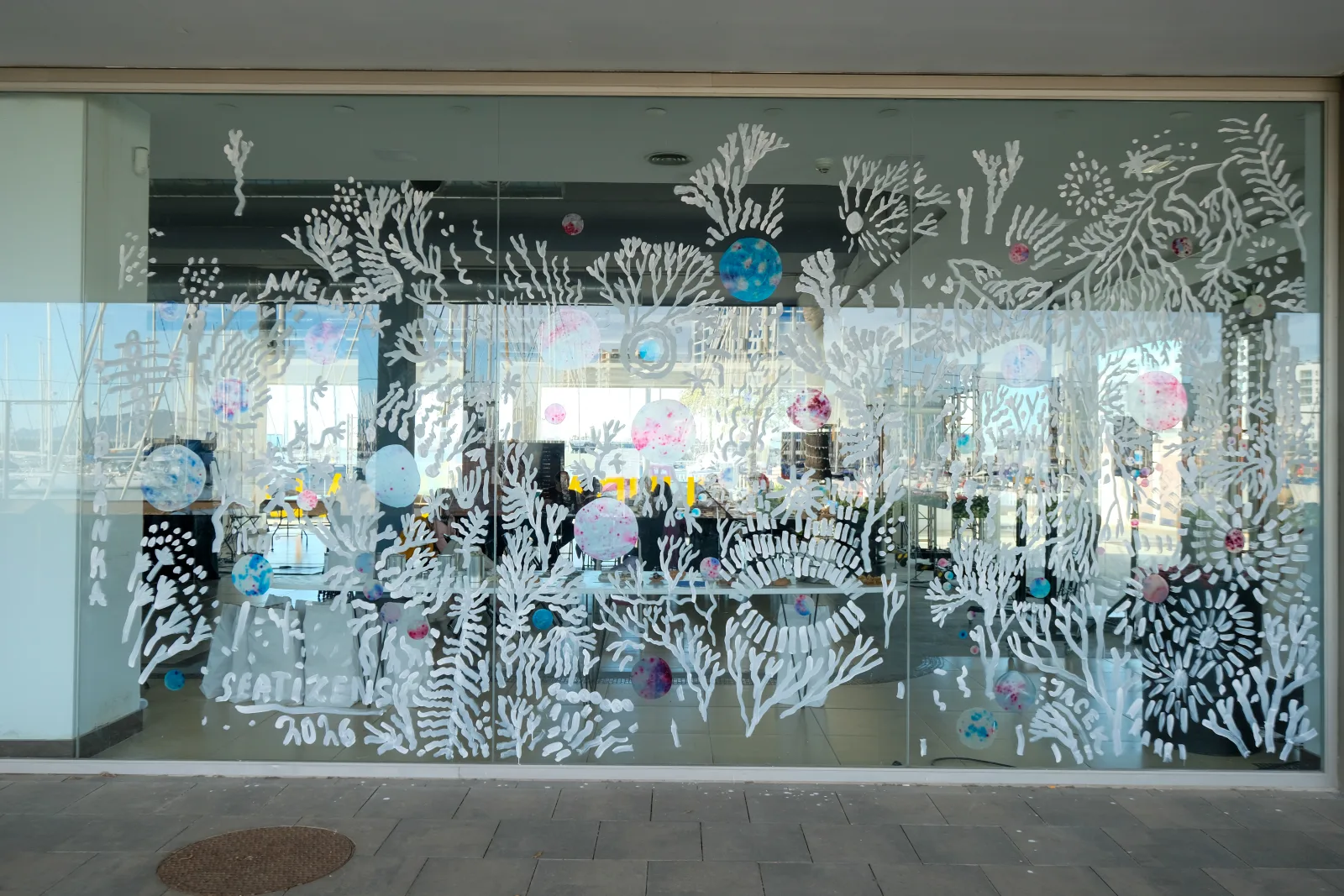 Amplio escaparate cubierto con un mural blanco de coral con burbujas de pigmento de colores en Demo Days